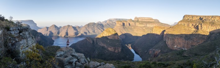 Hiker enjoying panorama, sunset at Blyde River Canyon with Three Rondawels peak, view of canyon