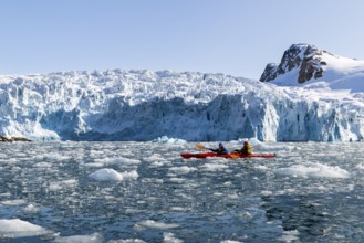 Canoe in front of glacier and mountain range with snow, sea, Fugelfjorden, Spitsbergen, Svalbard