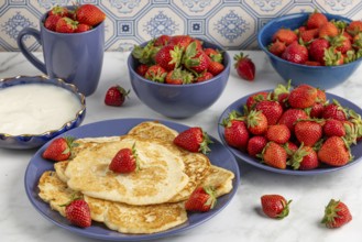 Pancakes with strawberries and yoghurt on blue crockery