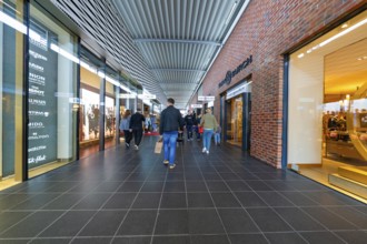 Visitors in the shopping centre surrounded by shops and modern architecture, Outlet City Metzingen,