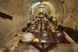 Table with various helmets in a long tunnel exhibition area, steel helmets, war museum, military
