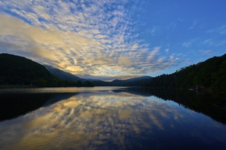 Beautiful lake view with impressive sky and calm water reflecting a peaceful sunrise, summer,