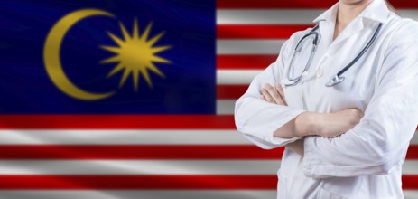Doctor with crossed arms on Malaysia flag. Malaysia health and care concept. Female doctor on