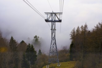 Cableway Tower in the cloud and the Autumn Forest in a Foggy Day on the Mountain in Locarno,