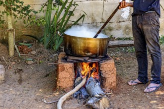 Person preparing a meal in the backyard on a wood-burning stove typically used in Minas Gerais,