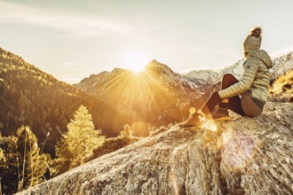Woman sitting thoughtfully at a feslen at autumn atmosphere during sunset in the Swiss Alps in the