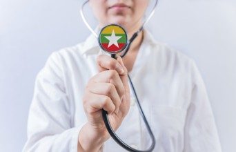 Female doctor holding stethoscope with Myanmar flag. National health system of Myanmar