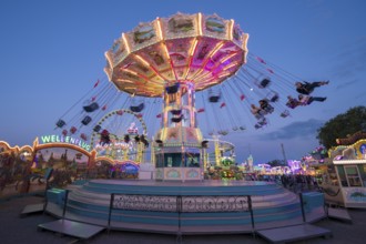 Colourfully illuminated carousel at a funfair in front of a night sky, chain carousel, spring