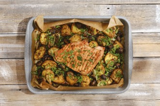 A roasted turkey breast rests atop a bed of golden, seasoned potatoes, vibrant herbs sprinkled over
