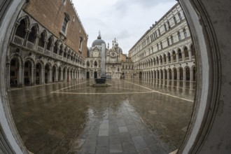 Wet pavement reflecting surrounding historical architecture in doge's palace courtyard on a rainy
