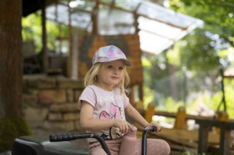 Girl, 3 years, blonde, sitting on bicycle in the garden, summer, Stuttgart, Baden-Württemberg,