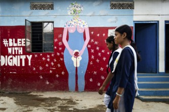 Students walk past a mural about female menstruation at Parijat Academy on the eve of Menstrual