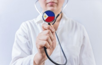 Female doctor holding stethoscope with Philippines flag. National health system of Philippines