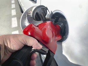 Male hand holding gas pump nossle pumping gas into vehicle