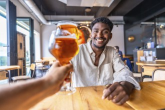 Waiter serving a refreshing glass of beer to a smiling young man in a stylish modern pub, creating