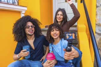 Three happy multi ethnic content creators filming a video blog with a gimbal and drinking smoothies