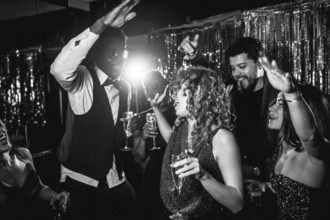 Group of stylish friends enjoying an exciting night out, dancing and sipping champagne at a lively