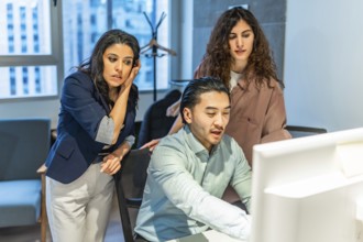 Diverse colleagues collaborating on a project, focusing on a computer screen, demonstrating