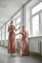 Two ballerinas in the corridor repeat movements, hone their skills