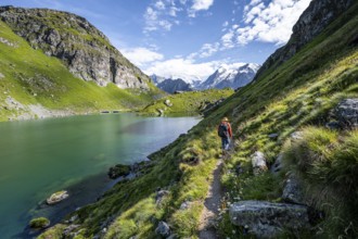 Mountaineer on a hiking trail at a mountain lake with a view of glaciated mountain peaks, Lac du
