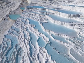 Detailed photo of cascading limestone terraces with turquoise-coloured water, aerial view, sinter