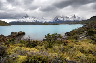Cloudy mountain range Cuernos del Paine, shore of the blue lake Lago Pehoe in the evening light,
