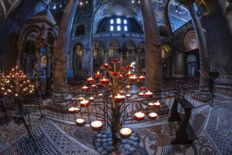 Several burning votive candles create a warm glow in the basilica di san marco, showcasing the