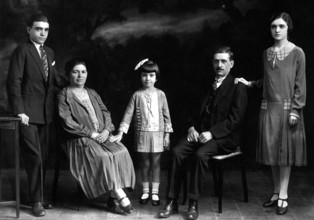 Family with children, 1930s, A family poses formally in a photo studio in elegant clothes,