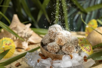 Coconut flakes fall on almond and chocolate confectionery in a coconut on ice cream with umbrellas