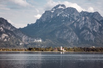 A lake against an impressive mountain backdrop with Neuschwanstein Castle in the background,