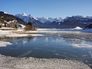 Frozen Sihlsee, reservoir, behind the snow-covered mountains Flübrig and Druesberg, Euthal, Canton