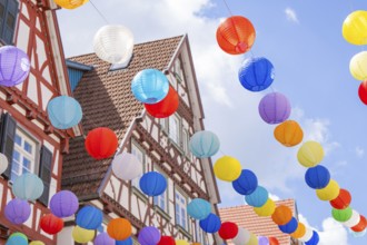 Lively balloons float above traditional half-timbered houses in a clear blue sky, Calw, Black