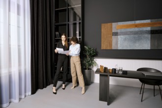 Two professional women engage in a discussion while reviewing documents in a stylish office