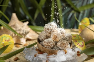 Coconut flakes fall on almond and chocolate confectionery in a coconut on ice cream with umbrellas