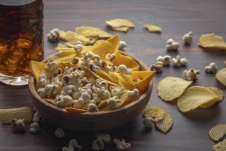 Wooden bowls with crisps and popcorn, next to a glass of cola