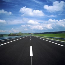 A straight stretch of a French motorway showcases smooth asphalt and clear lane markings. Lush