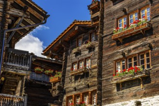 Old wooden houses in log construction, decorated with flowers, historic village centre, Grimentz,
