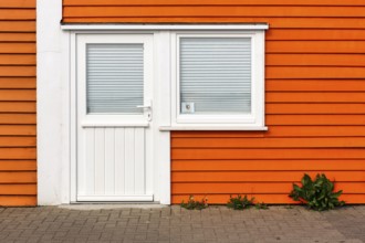 Colourful lobster shack, orange wooden façade with door and window, registry office sticker, façade