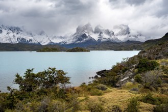 Cloudy mountain range Cuernos del Paine, shore of the blue lake Lago Pehoe in the evening light,