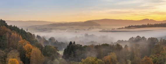 Landscape in Franconian Switzerland in autumn, view over colourful forests with morning mist at