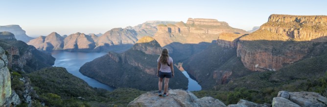 Hiker enjoying panorama, sunset at Blyde River Canyon with Three Rondawels peak, view of canyon