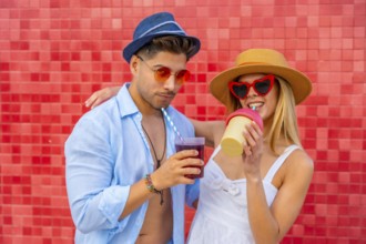 Happy couple enjoying colorful beverages on a summer day, showcasing trendy fashion and a vibrant