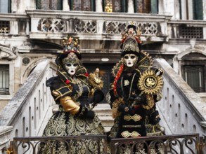 Two people in costume posing on a staircase, Venetian costumes with masks, Carnival in Venice,