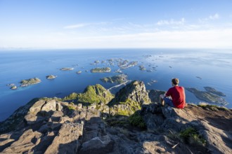 View of numerous small rocky islands with houses, mountaineers on the summit of Festvågtind, view