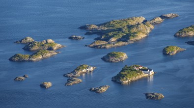 Small rocky islands with individual houses in the sea, archipelago islands, near Henningsvær,