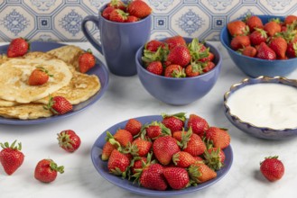 An appetising display of strawberries and pancakes on a table with blue crockery
