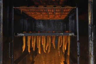 Smoking fish over beechwood fire in large metal smoker oven on the island Usedom in the Baltic Sea,