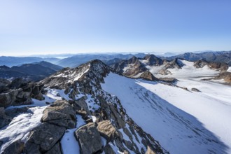 Narrow rocky ridge at the Wilder Freiger summit, picturesque high mountain landscape with snow,