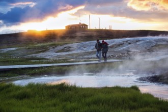 Walker on wooden path, sulphur vapour, geothermal area Hveravellir, sunset, icelandic highlands,