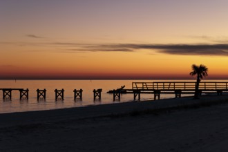 Sunset behind dilapidated fishing pier damaged by hurricanes on the Mississippi Gulf Coast in Long